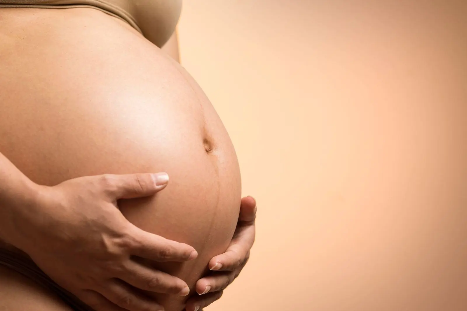 Mujer embarazada sosteniendo su vientre con ambas manos